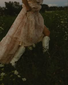 a woman in a dress and cowboy boots is posing for a photo on the grass