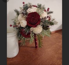 a bouquet of flowers sitting on top of a wooden table next to a white jar