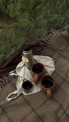 two coffee cups sitting on top of a blanket