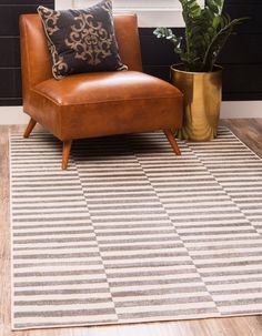 a brown chair sitting on top of a wooden floor next to a potted plant