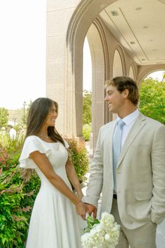 a man in a suit and tie standing next to a woman in a wedding dress