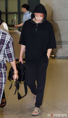 a man walking through an airport carrying a black bag and a woman in plaid pants