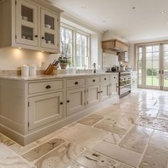 a large kitchen with marble flooring and white cabinetry on the walls, along with glass doors leading to an outside patio