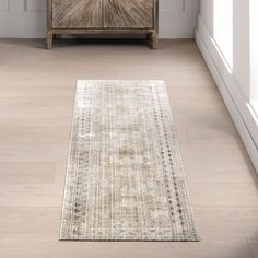 a beige area rug in front of a wooden cabinet