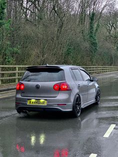 a silver car parked on the side of a wet road