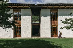 a person walking in front of a white building with wooden doors and windows on the outside