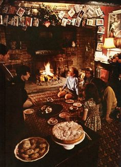 a group of people sitting around a fire place with pies on the table in front of them