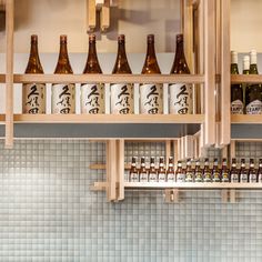 bottles are lined up on shelves in a room with tiled walls and flooring,