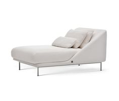 a white chaise lounger with pillows on it's back and side legs