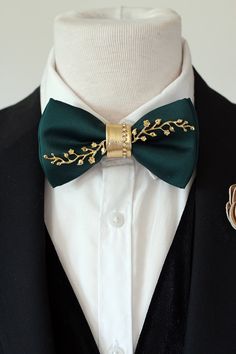 a man wearing a green bow tie and gold brooch on his lapel collar