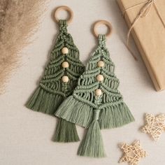 two crocheted christmas trees with wooden ornaments next to a brown box and string