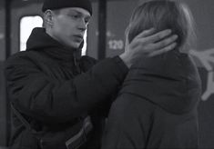 a man and woman standing next to each other in front of a subway train car