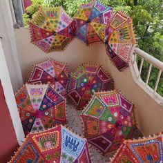 many colorful umbrellas are laying on the ground near some stairs and trees in the background