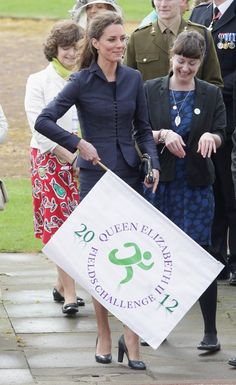 the queen is holding a banner while walking with other people