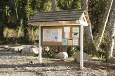 a sign in the middle of a dirt area with rocks and trees around it that has information about wildlife