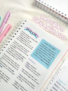 an open notebook sitting on top of a table next to some pens and paper clips