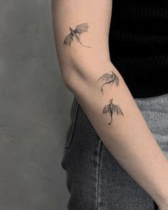 a woman's arm with three small bats on it