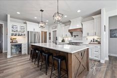 a large kitchen with white cabinets and wooden floors