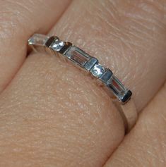 This is a classic ring.   Three  4mm x 3mm emerald cut cubic zirconia stones and two 3mm round stones sit alternating across this band.  nice stacking style as the stones are bezel set. Stamped 925  size 8.75 1.8 grams with stones band is 3mm wide #BKB-RNG88 Please take a look at my other Etsy shop NautiCatDesigns for unique gift items made of shells and stones! https://www.etsy.com/shop/NauticatDesigns?ref=ss_profile Cubic Zirconia Stackable Rings For Anniversary, Silver Emerald Cut Half Eternity Band, Silver Emerald-cut Half Eternity Band, Diamond White Emerald-cut Stackable Rings For Anniversary, Silver Cubic Zirconia Eternity Band With Emerald Cut, Silver Emerald Cut Cubic Zirconia Eternity Band, Goth Pendant, Silver Eternity Ring, Bad Kitty