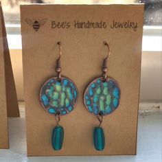 a pair of earrings with blue and green designs hanging from it's earwires