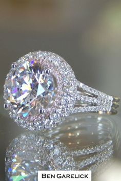 a close up view of a diamond ring with its reflection on the ground and in the background