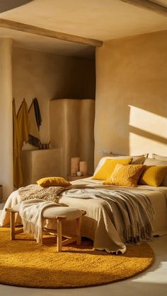 a bed with yellow pillows and blankets on top of it next to a rug in front of a window