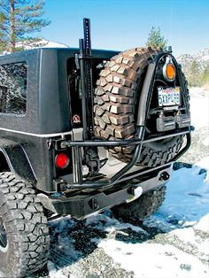 the back end of a black jeep parked on snow covered ground