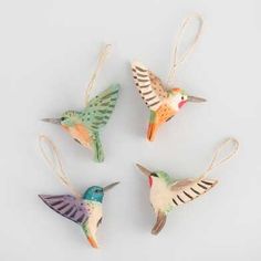 four ceramic hummingbirds hanging from twine strings on a white surface, each with different colors and patterns