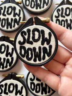 a hand is holding several small black and white buttons with the words slow down on them