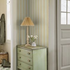 a green dresser sitting next to a lamp on top of a wooden table in a room