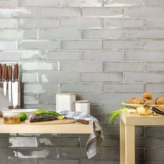 two wooden tables sitting next to each other in front of a white brick wall and floor