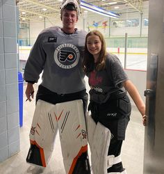 a man standing next to a woman in hockey gear