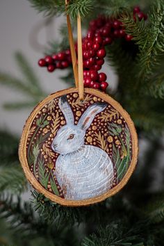 a wooden ornament with a white rabbit on it's side hanging from a christmas tree