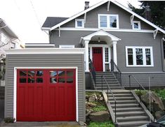 a gray house with a red garage door