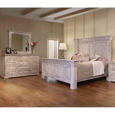 a white bed sitting on top of a wooden floor next to a dresser and mirror