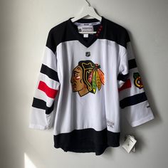 a black and white hockey jersey hanging up on a hanger next to a wall