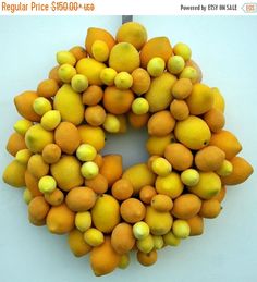 a wreath made out of lemons and oranges on a white wall with a gray background