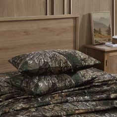 a bed covered in camouflage sheets and pillows