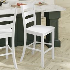 two white chairs sitting next to each other in a kitchen