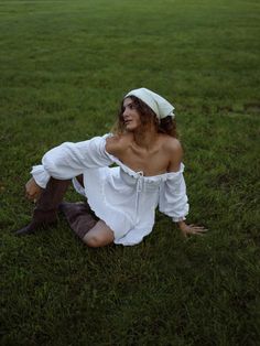 a woman sitting in the grass wearing a white dress