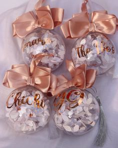 four personalized glass ornaments with bows on them