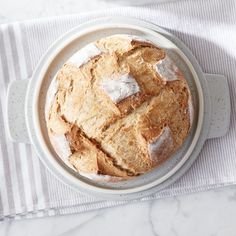 a bowl filled with bread sitting on top of a white table next to a napkin