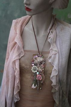 a mannequin head wearing a necklace with flowers and feathers on it's neck