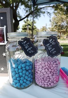 two mason jars filled with candy sitting on top of a table next to an umbrella