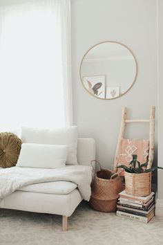 a living room with a white couch and some books on the floor next to a window