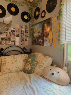 there is a bed with many records on the wall above it and a stuffed bear