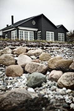 a black house sitting on top of a rocky hillside