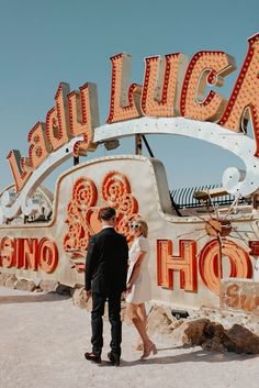 a man and woman standing in front of a neon sign