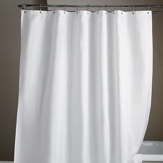 a white shower curtain hanging from a metal rod