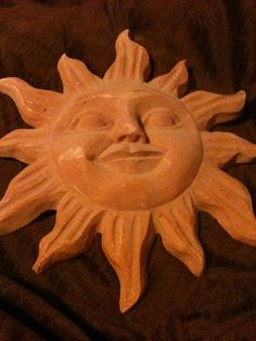 a ceramic sun face sitting on top of a bed